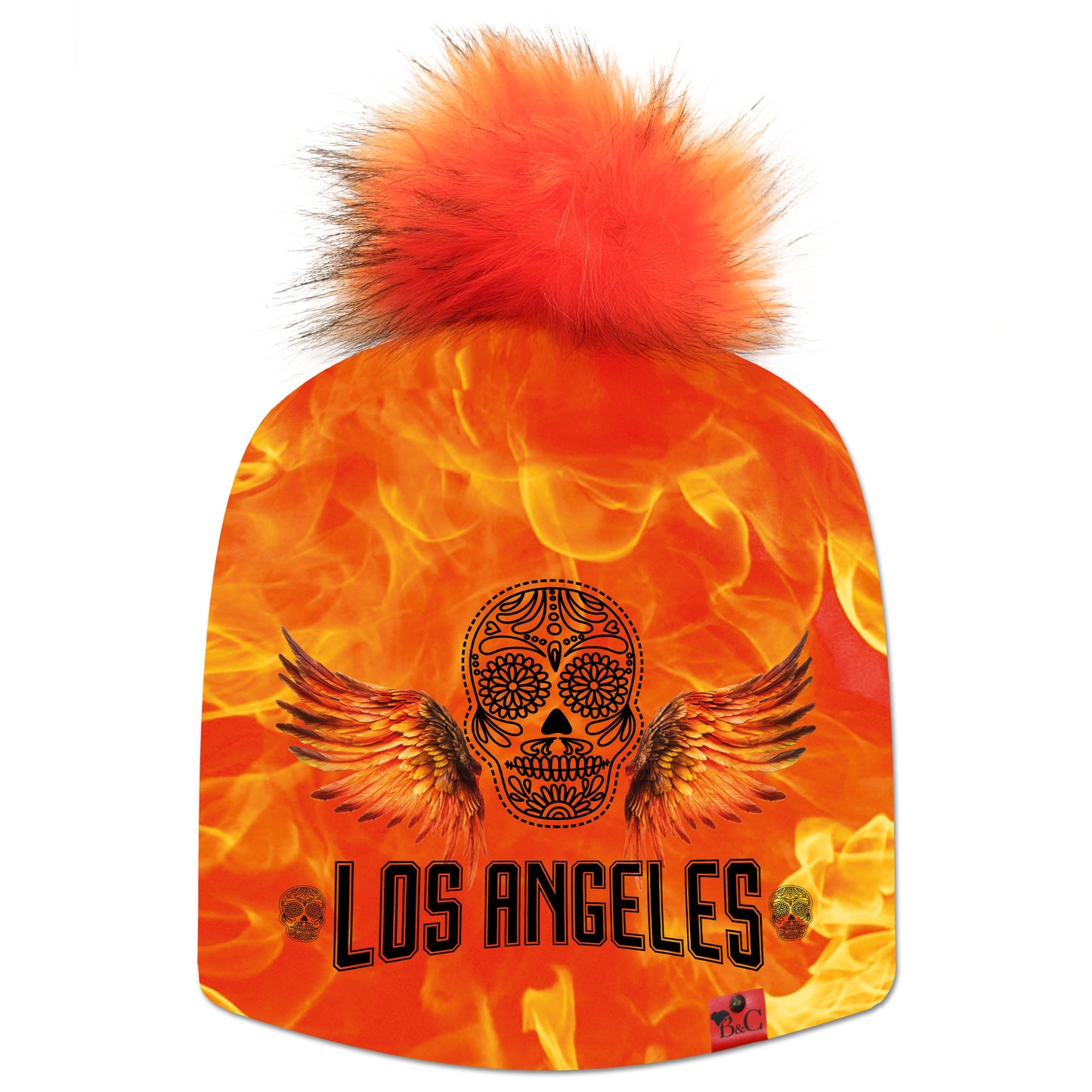 Bonnet Sunset Bld pour enfants avec une tête de mort, des ailes sur un fond orangé en flamme et l'inscription "Los Angeles" et son pompon Renard en fourrure synthétique. Il est signé Beanie and Clyde grâce à son étiquette en cuir synthétique rouge.