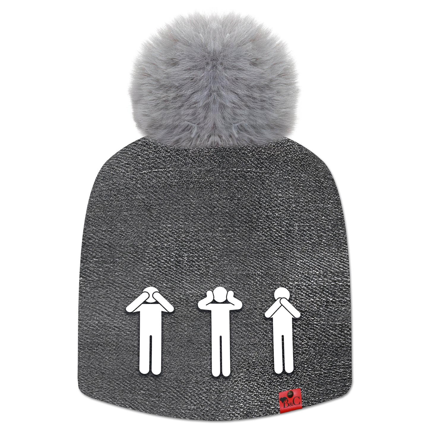 Bonnet Yoko pour hommes et femmes, habillé d’un motif effet jean noir délavé, surmonté d’un pompon gris en fourrure synthétique. Il est orné de l’étiquette en cuir rouge signée Beanie & Clyde, avec au premier plan trois pictogrammes représentant les singes de la sagesse : ne rien voir, ne rien entendre, ne rien dire.