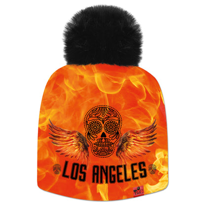 Bonnet Bikker avec une tête de mort, des ailes sur un fond orangé en flamme et l'inscription "Los Angeles" et son pompon en fourrure synthétique noir. De quoi apporter une touche audacieuse à votre tenue.