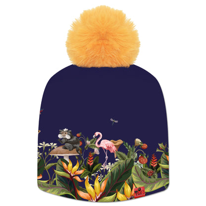 Bonnet Candi pour femmes avec un motif floral, un flamant rose, un singe, un oiseau, une libellule sur un fond bleu. Il est accompagné de son pompon Jaune Banane en fourrure synthétique pour une touche lumineuse.