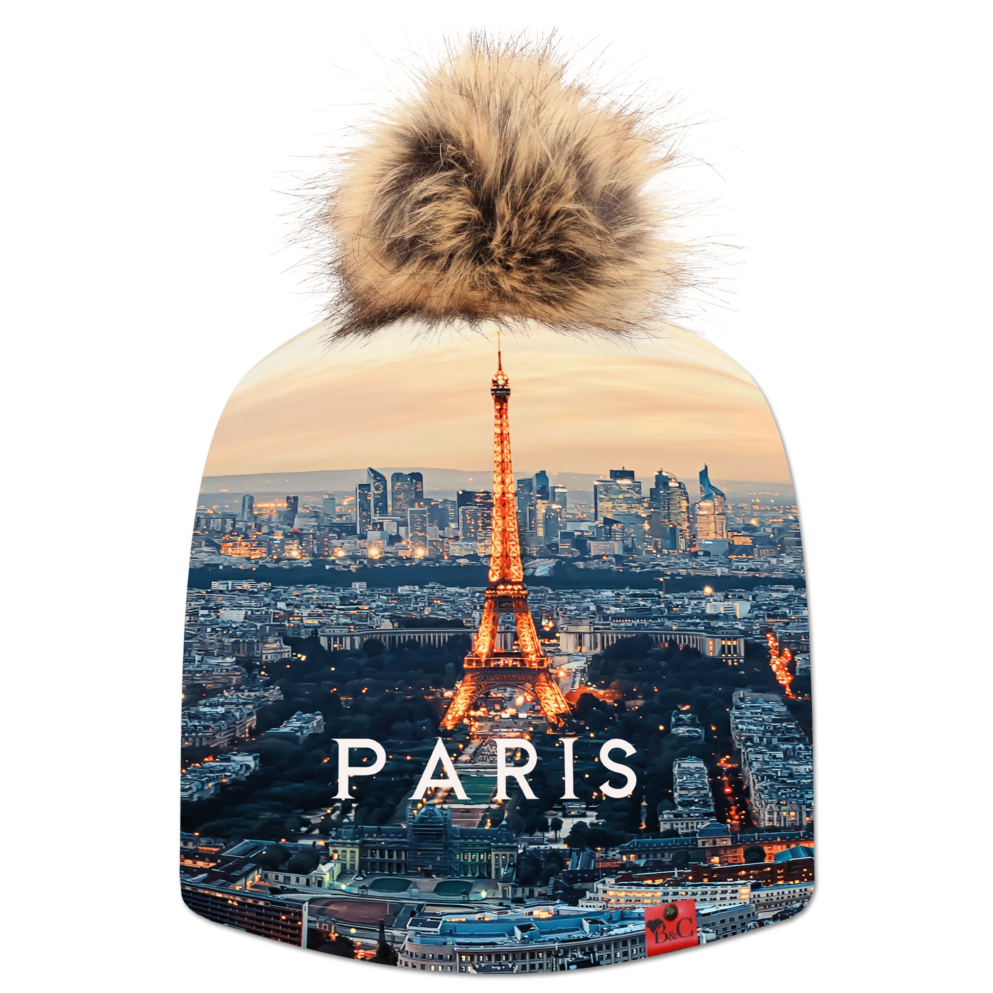 Bonnet Eiffel pour enfants, avec en fond vu sur Paris et la tour Eiffel et l'inscription "Paris" au centre. Le bonnet est accompagné de son pompon Marmotte en fourrure synthétique et son étiquette en cuir rouge signée Beanie and Clyde.