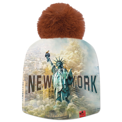 Bonnet Trump pour hommes et femmes, avec un paysage New Yorkais et la statue de la liberté en premier plan. Accompagné de son pompon Ecureuil en fourrure synthétique et de son étiquette en cuir synthétique rouge signée Beanie and Clyde.